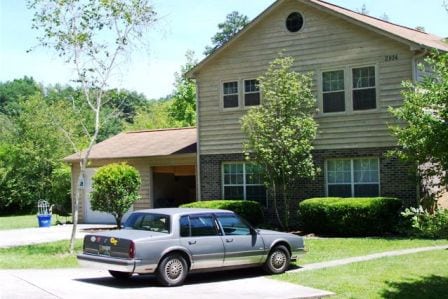 yellow traditional duplex with car in driveway