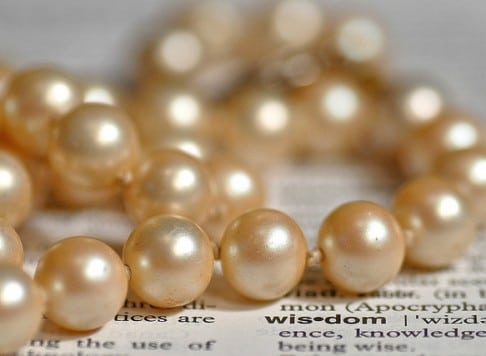 pearls on a newspaper with the word wisdom highlighted
